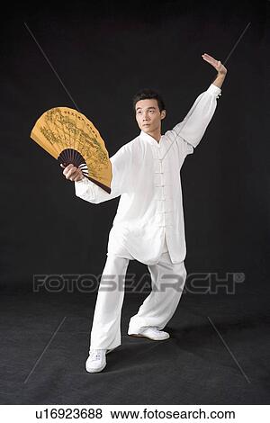 Young man in martial arts pose with fan in studio shot View Large Photo Image Stock Photo - Young man in martial arts pose with fan in studio shot. Fotosearch