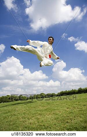 Young man in martial arts uniform kicking leg in mid air View Large Photo Image Stock Image - Young man in martial arts uniform kicking leg in mid air. Fotosearch