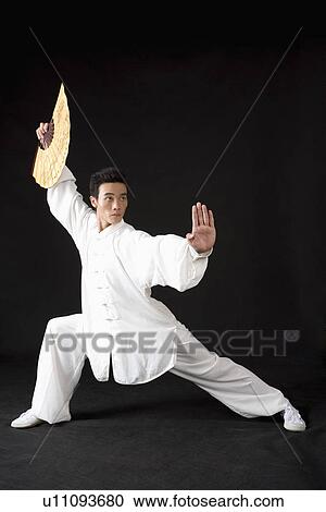 Stock Image - Young man practicing martial arts with fan. Fotosearch