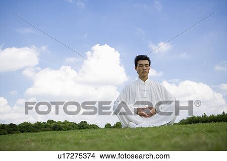 Young man sitting on lawn with legs crossed View Large Photo Image Picture - Young man sitting on lawn with legs crossed. Fotosearch