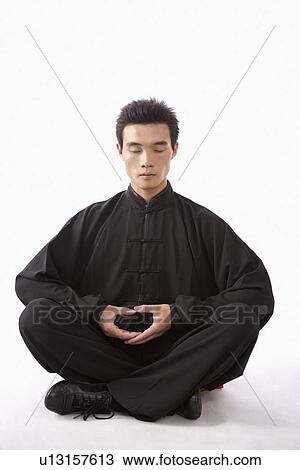 Stock Image - Young man sitting with legs crossed. Fotosearch