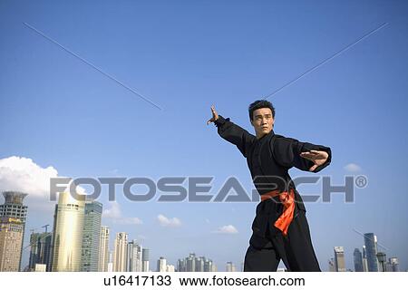 Stock Image - Young man wearing martial arts uniform performing the Kung Fu. Fotosearch