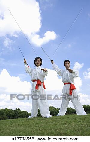 Young woman and man doing kung-fu moves with sword View Large Photo Image Stock Photograph - Young woman and man doing kung-fu moves with sword. Fotosearch