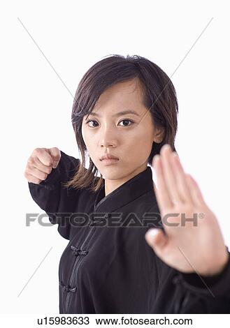 Stock Image - Young woman in martial arts pose against white background. Fotosearch