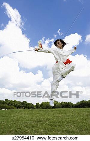 Stock Image - Young woman practicing martial arts with swords. Fotosearch