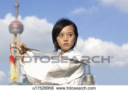 Stock Photograph - Young woman practicing martial arts with swords. Fotosearch