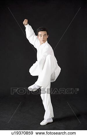 Stock Photo - Young woman standing on one leg against black background. Fotosearch