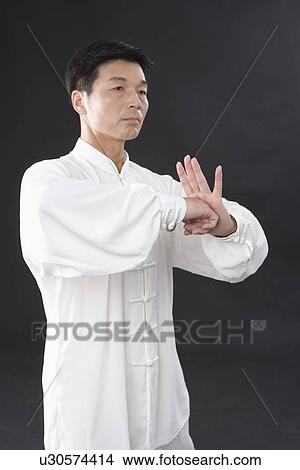 Picture - Man practicing Tai Chi against black background. Fotosearch