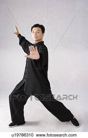 Stock Image - Man practicing Tai Chi against white background. Fotosearch
