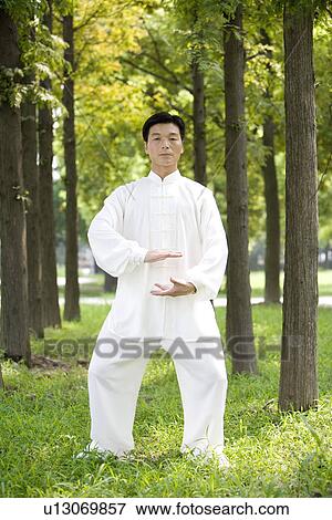 Stock Photo - Man practicing Tai Chi amongst trees, portrait. Fotosearch