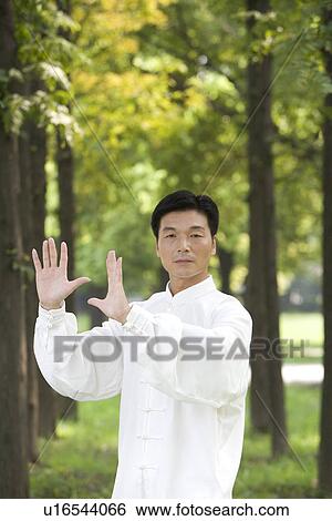 Stock Photograph - Man practicing Tai Chi amongst trees. Fotosearch