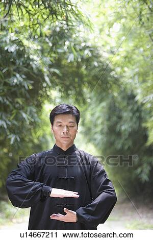 Stock Image - Man practicing Tai Chi in bamboo grove. Fotosearch