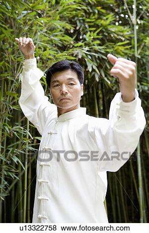 Stock Photo - Man practicing Tai Chi in bamboo grove, portrait. Fotosearch