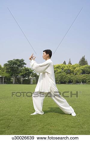 Stock Photo - Man practicing Tai Chi on lawn. Fotosearch