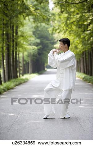 Stock Photo - Man practicing Tai Chi on treelined footpath. Fotosearch