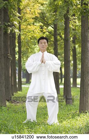 Stock Image - Mature man in prayer position in botany garden. Fotosearch