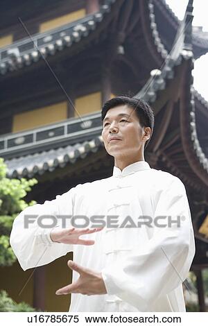Stock Photography - Mature man practicing Tai Chi in front of Longhua temple. Fotosearch
