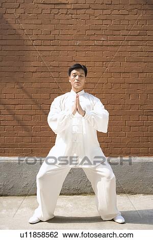 Stock Image - Mature man practicing Tai Chi in prayer position. Fotosearch