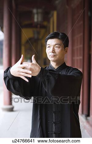 Stock Image - Mature man practicing Tai Chi in corridor. Fotosearch