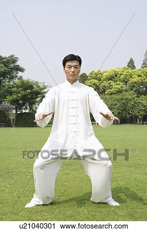 Stock Image - Mature man practicing Tai Chi on lawn. Fotosearch