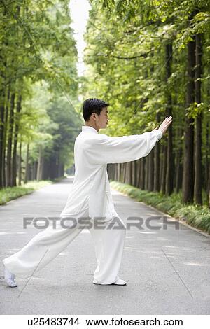 Picture - Mature man practicing Tai Chi on footpath. Fotosearch