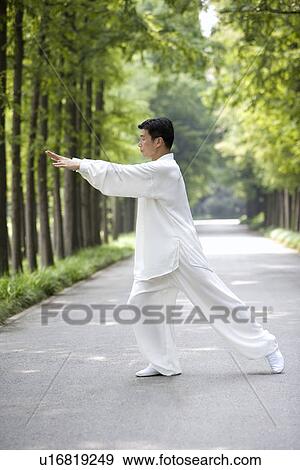 Stock Photo - Mature man practicing Tai Chi on treelined footpath. Fotosearch
