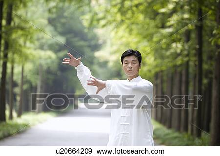 Stock Photo - Mature man practicing Tai Chi on treelined footpath. Fotosearch