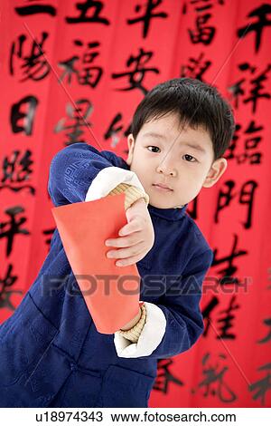Stock Image - Boy in Chinese traditional clothes holding red envelopes. Fotosearch