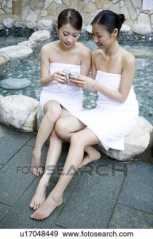 Two young women sitting by pool, talking View Large Photo Image Stock Photo - Two young women sitting by pool, talking. Fotosearch
