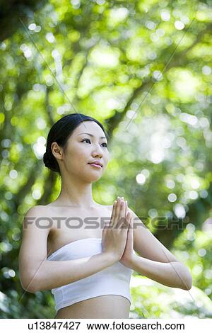 Stock Photo - Young woman in meditating position in woods. Fotosearch