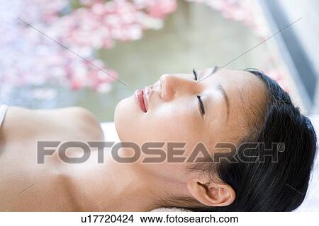 Picture - Young woman resting by rose petal pool. Fotosearch