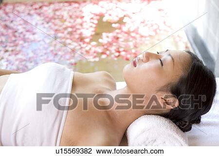 Stock Image - Young woman resting by rose petal pool. Fotosearch