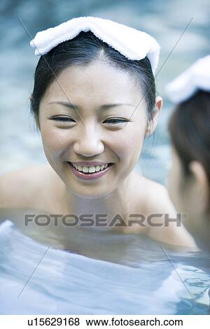 Stock Photo - Young woman with towel on head, bathing in hot spring. Fotosearch