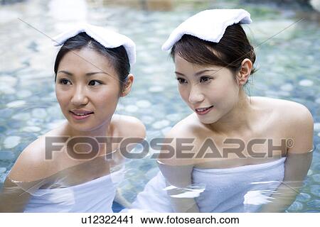 Stock Image - Young women with towel on head, bathing in hot spring. Fotosearch