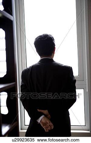 Stock Photography - Businessman by window, rear view. Fotosearch