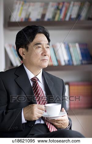 Stock Photography - Businessman holding a cup of coffee in office. Fotosearch