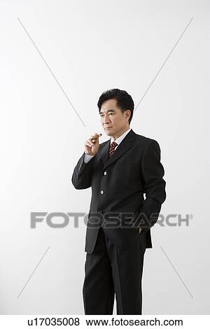 Stock Photo - Businessman holding cigar in studio shot. Fotosearch