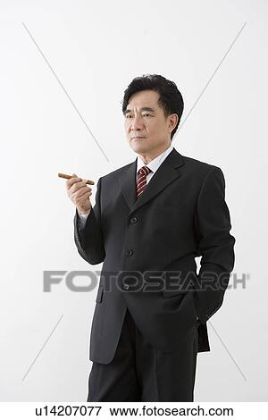 Stock Photo - Businessman holding cigar, portrait, close up. Fotosearch