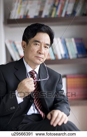 Stock Image - Businessman holding glass in office. Fotosearch