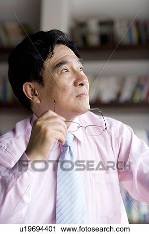 Stock Image - Businessman holding glass looking through window. Fotosearch