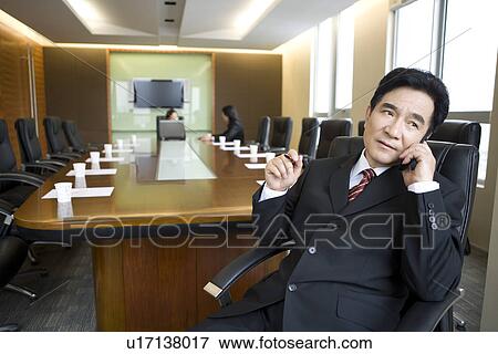 Businessman on the phone, two businesswomen discussing in board room View Large Photo Image Stock Photo - Businessman on the phone, two businesswomen discussing in board room. Fotosearch