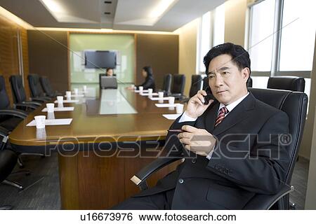 Businessman on the phone, two colleagues talking in boardroom View Large Photo Image Stock Photograph - Businessman on the phone, two colleagues talking in boardroom. Fotosearch