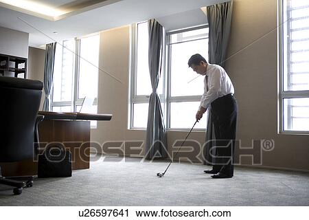 Businessman playing golf in office View Large Photo Image Stock Image - Businessman playing golf in office. Fotosearch