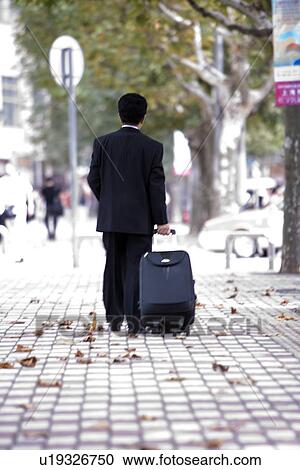Businessman pulling suitcase outdoors View Large Photo Image Stock Image - Businessman pulling suitcase outdoors. Fotosearch