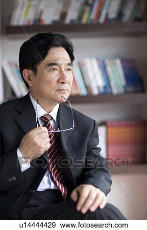 Businessman sitting on chair holding glass in office View Large Photo Image Stock Photo - Businessman sitting on chair holding glass in office. Fotosearch