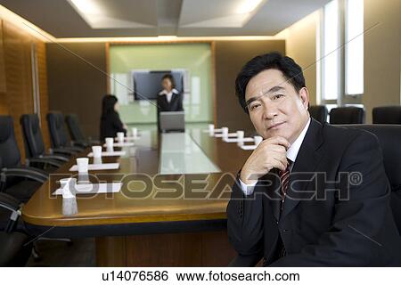 Businessman sitting on chair in board room View Large Photo Image Stock Photograph - Businessman sitting on chair in board room. Fotosearch