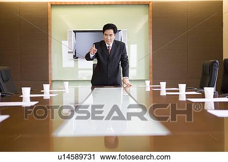 Businessman speaking alone in board room View Large Photo Image Stock Image - Businessman speaking alone in board room. Fotosearch