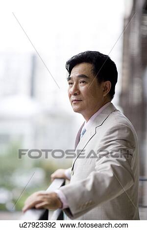 Stock Image - Businessman standing by railing. Fotosearch