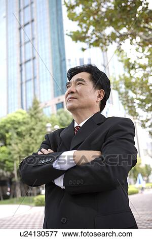 Stock Photo - Businessman standing with arms crossed outdoors. Fotosearch
