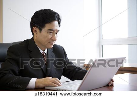 Stock Image - Businessman using laptop in office. Fotosearch